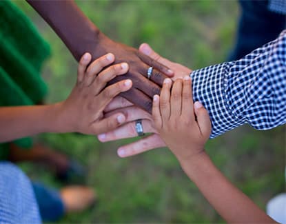 Many hands joined together in the centre of a circle